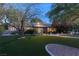 Inviting brick home with manicured lawn and mature trees, illuminated by landscape lighting at twilight at 2001 Silver Ave, Las Vegas, NV 89102
