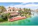 Beautiful multi-story waterfront home, a red dock, green grass, lush landscaping, and serene water view at 2925 Coast Line Ct, Las Vegas, NV 89117