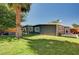 Backyard view of a charming home with a large lawn, mature trees, and a comfortable hammock on the patio at 3013 Roseville Way, Las Vegas, NV 89102