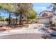 Charming home exterior features a two-car garage, desert landscaping, and mature trees in a residential neighborhood at 3200 Mariner Bay St, Las Vegas, NV 89117