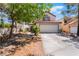 Charming home exterior features a two-car garage, desert landscaping, and mature trees in a residential neighborhood at 3200 Mariner Bay St, Las Vegas, NV 89117