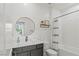 Modern bathroom featuring a sleek vanity, round mirror, and shower-tub combo at 3369 Ponicelli Ln, Henderson, NV 89044