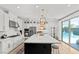 Modern kitchen features stainless appliances, large island, and sliding doors leading to the outdoor pool at 3369 Ponicelli Ln, Henderson, NV 89044