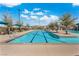 Community swimming pool with lounge chairs, tables, and umbrellas under a blue sky at 3369 Ponicelli Ln, Henderson, NV 89044