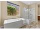 Luxury bathroom featuring a freestanding tub and a glass-enclosed shower, highlighted by a garden view at 34 Costa Tropical Dr, Henderson, NV 89011