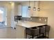 Bright kitchen featuring white cabinets, gray backsplash, quartz countertops, and island with barstool seating at 3447 Sw Covilha Ln, Henderson, NV 89044