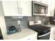 Close up of a modern kitchen showcasing stainless steel appliances and gray tiled backsplash at 3447 Sw Covilha Ln, Henderson, NV 89044