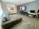 Open-concept living room with stylish gray sofa and TV wall at 3447 Sw Covilha Ln, Henderson, NV 89044