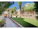 Backyard featuring a well-maintained lawn, lovely landscaping, privacy wall, and a covered patio at 3873 Palm Island Ct, Las Vegas, NV 89147