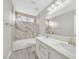 Bright bathroom featuring a marble-walled shower-over-tub and double sink vanity with quartz countertops at 600 Baysville Ct, Las Vegas, NV 89144