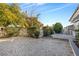 Landscaped backyard with gravel ground cover, white fence and mature trees creating a serene and low-maintenance outdoor space at 620 Avenue H, Boulder City, NV 89005