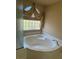 A soaking tub sits below a glass block window with decorative curtains at 6277 Mustang Spring Ave, Las Vegas, NV 89139