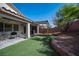 Manicured backyard featuring artificial turf, privacy wall, and covered patio with seating at 6333 Sterling Ranch Way, North Las Vegas, NV 89081