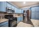 Well-equipped kitchen featuring stainless steel appliances, granite countertops, and blue cabinets at 6333 Sterling Ranch Way, North Las Vegas, NV 89081