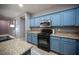 Well-equipped kitchen featuring sleek, stainless steel appliances and granite countertops and blue cabinets at 6333 Sterling Ranch Way, North Las Vegas, NV 89081