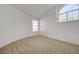 Bright bedroom featuring a neutral carpet, white walls, and a large arched window at 7528 Golden Yucca Dr, Las Vegas, NV 89147