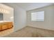 View into the bedroom with neutral carpet with the bathroom adjacent and a bright window at 7528 Golden Yucca Dr, Las Vegas, NV 89147
