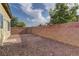 The backyard is enclosed by a red brick wall and covered with small red stones at 7919 Dexter Falls St, Las Vegas, NV 89149
