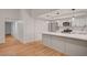 Modern kitchen featuring light grey cabinetry, quartz countertops, stainless appliances, and wood flooring at 8412 Mulcahy Ave, Las Vegas, NV 89145