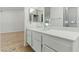 Bright bathroom featuring white cabinets, a wide mirror, and neutral tile at 9116 Cypress Point Way, Las Vegas, NV 89117