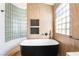 Bathroom featuring a soaking tub, modern fixtures, tiled walls, and ample natural light at 912 Pro Players Dr, Las Vegas, NV 89134