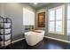 Modern bathroom with a freestanding tub, plantation shutters, and dark tile flooring at 10526 Harvest Wind Dr, Las Vegas, NV 89135