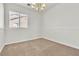Empty bedroom featuring a chandelier, neutral carpet, and a window with blinds at 10987 Santorini Dr, Las Vegas, NV 89141
