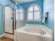 Bathroom featuring a soaking tub, glass-enclosed shower, and arched window at 1126 Winter Storm Dr, Henderson, NV 89052