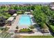 Aerial view of a luxurious neighborhood pool featuring lounge chairs, umbrellas, green landscaping, and mature trees at 11375 Ogden Mills Dr # 103, Las Vegas, NV 89135