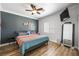 Cozy bedroom with ceiling fan, mounted TV, and dark accent wall, with hardwood style floors at 1345 Morning Sun Way, Las Vegas, NV 89110