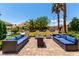 An inviting outdoor patio featuring comfortable seating, a fire pit, and lush landscaping, perfect for entertaining at 3825 Manhattan Bridge Pl, North Las Vegas, NV 89032