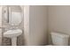 A half bathroom featuring a white pedestal sink, a round mirror and a toilet at 389 Fringe Ruff Dr, Las Vegas, NV 89148