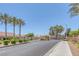 Gated community entrance with lush landscaping, sidewalks, and palm trees under a clear blue sky at 4369 Meadowlark Wing Way, North Las Vegas, NV 89084