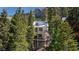 Exterior view of a multi-story home featuring multiple balconies surrounded by lush trees with mountain views at 4778 Knotty Pine Way, Las Vegas, NV 89124
