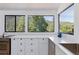 Bright kitchen features white cabinets, stone countertops, stainless sink, and scenic mountain views from the windows at 4778 Knotty Pine Way, Las Vegas, NV 89124