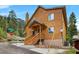 Exterior view of wooden house with covered porch, near tree-lined mountains and a corner street at 4830 Silver Tip Way, Mount Charleston, NV 89124