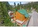 Charming cabin exterior with a green roof, natural wood siding, and a quaint fenced patio area, nestled in a forest setting at 4830 Silver Tip Way, Mount Charleston, NV 89124