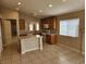 This kitchen has an island, neutral countertops and flooring, with a view into another room at 5605 Midnight Breeze St, North Las Vegas, NV 89081