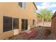A tan two-story home with a fenced backyard including a brick patio and gravel at 5641 Vassar Meadow St, Las Vegas, NV 89148