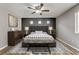 Comfortable bedroom featuring a ceiling fan, three windows, decorative lamps and dark accent wall at 6953 Graceful Cloud, Henderson, NV 89011