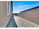 Long paver driveway leads to gate, alongside neutral stucco house and tall block wall, offering private entrance at 7036 Winstar St, Las Vegas, NV 89131