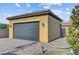 Exterior of detached two-car garage with gray door, stucco siding, and paver driveway surrounded by greenery at 7036 Winstar St, Las Vegas, NV 89131