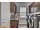 Convenient laundry room features wooden cabinets, modern washer and dryer, and a small window for natural light at 7036 Winstar St, Las Vegas, NV 89131
