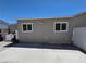 Backyard featuring a gray stucco exterior, two windows, concrete slab, and some misc storage at 7108 Moon Ct, Las Vegas, NV 89145
