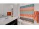 A well-lit bathroom has a patterned shower curtain and orange towels at 794 Sunny Sagebrush St, Henderson, NV 89011