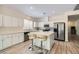 Bright kitchen featuring white cabinets, stainless steel appliances, a center island with seating, and wood-look floors at 11074 Caramel Crest Ct, Las Vegas, NV 89135