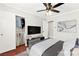 Virtually staged main bedroom with hard wood floors, ceiling fan, mounted TV, and closet at 11649 Royal Derwent Dr, Las Vegas, NV 89138