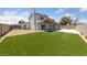 Expansive backyard features lush artificial grass, fenced perimeter, and covered patio at 1511 Irene Dr, Boulder City, NV 89005