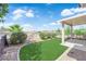 Beautiful backyard features green turf, desert landscaping, and a covered patio with ample space for relaxing at 2504 Libretto Ave, Henderson, NV 89052
