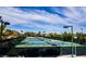 Outdoor tennis courts feature well-maintained blue and green surfaces, surrounded by fencing and lights, set against a blue sky at 2545 Divine Sky Dr, Henderson, NV 89044